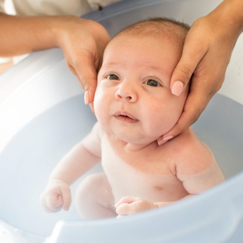 Adorable newborn baby having a bath by the mother