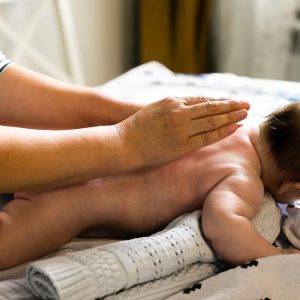Mother makes newborn baby massage apply oil on the hand